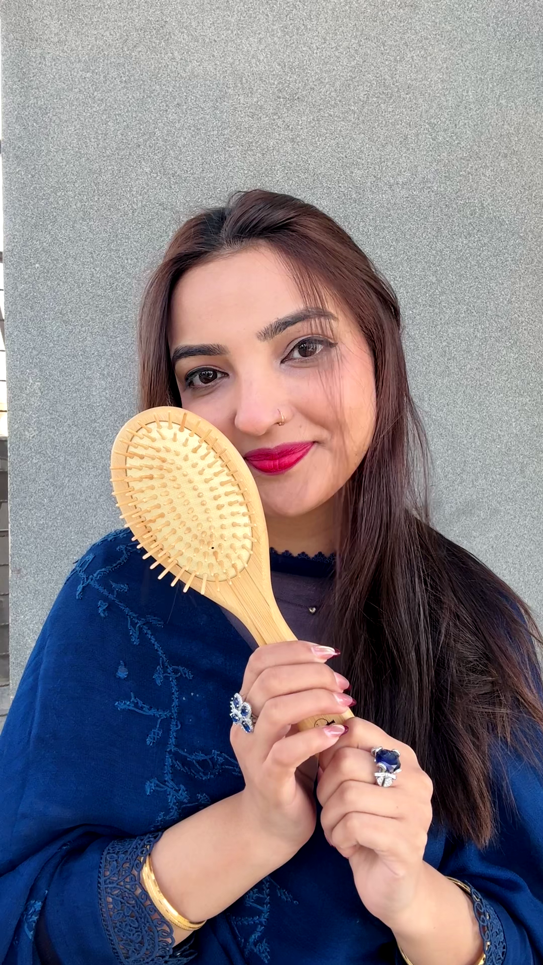 Woman holding a yellow hairbrush against a gray background