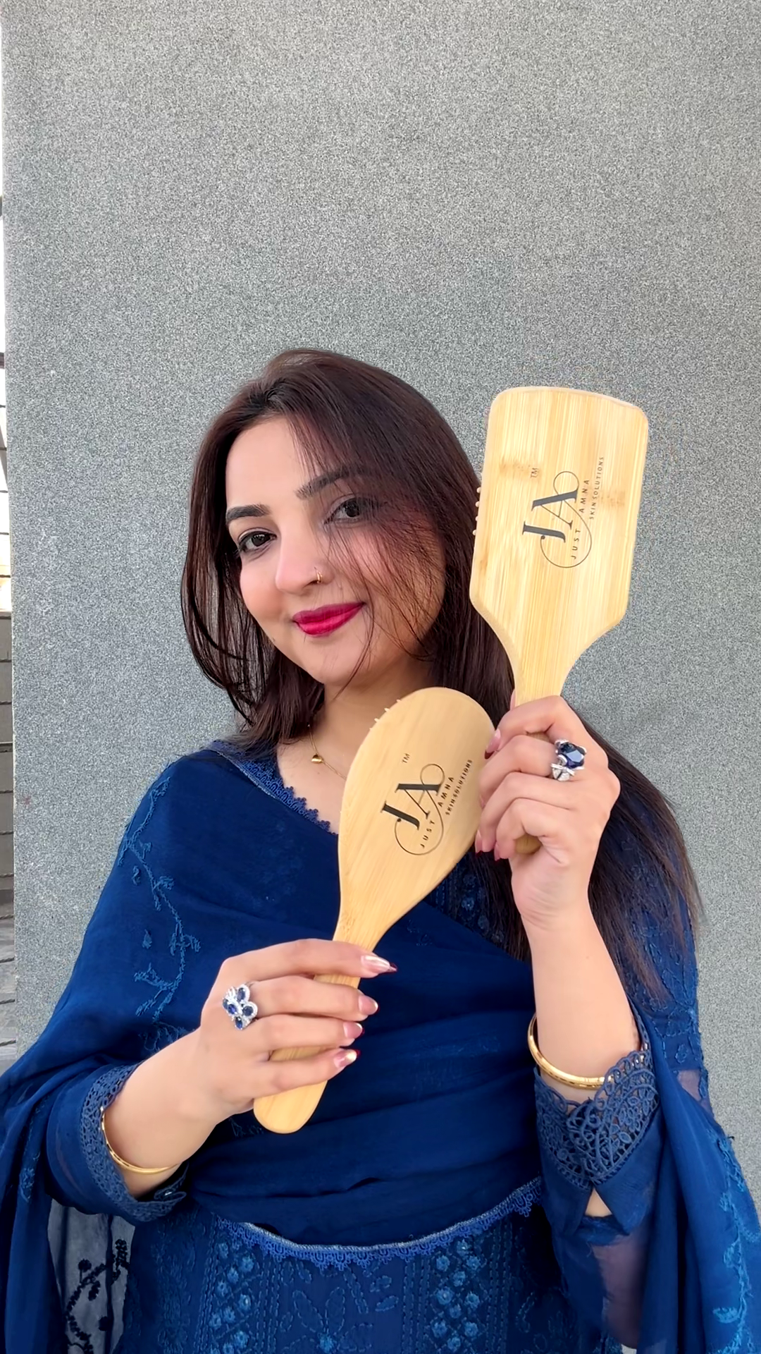 Woman holding two wooden hairbrushes against a gray background