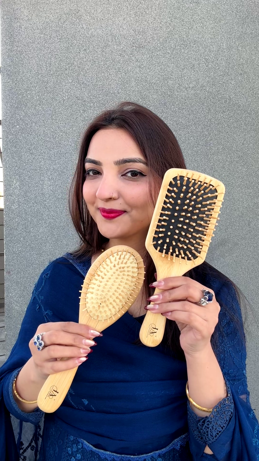 Woman holding two wooden hairbrushes against a gray background